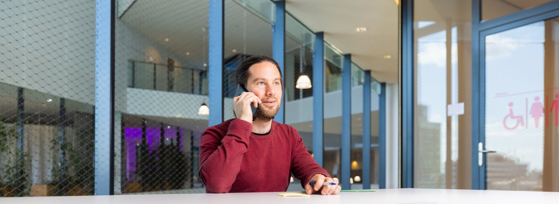 Vergunningverlener Bjorn zit achter een bureau te bellen in het stadskantoor
