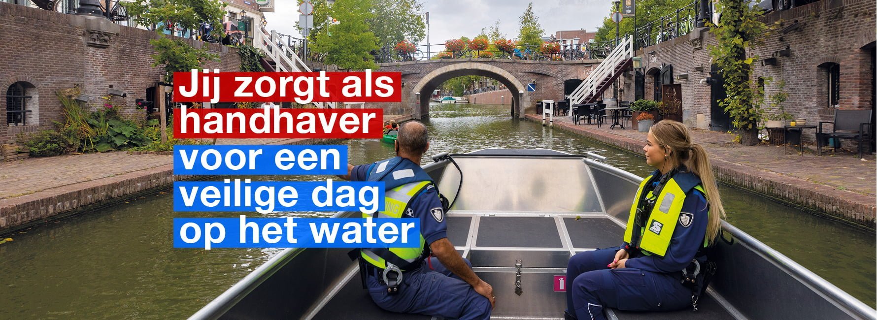 Twee handhavers aan het werk in een boot op het water van de Oudegracht