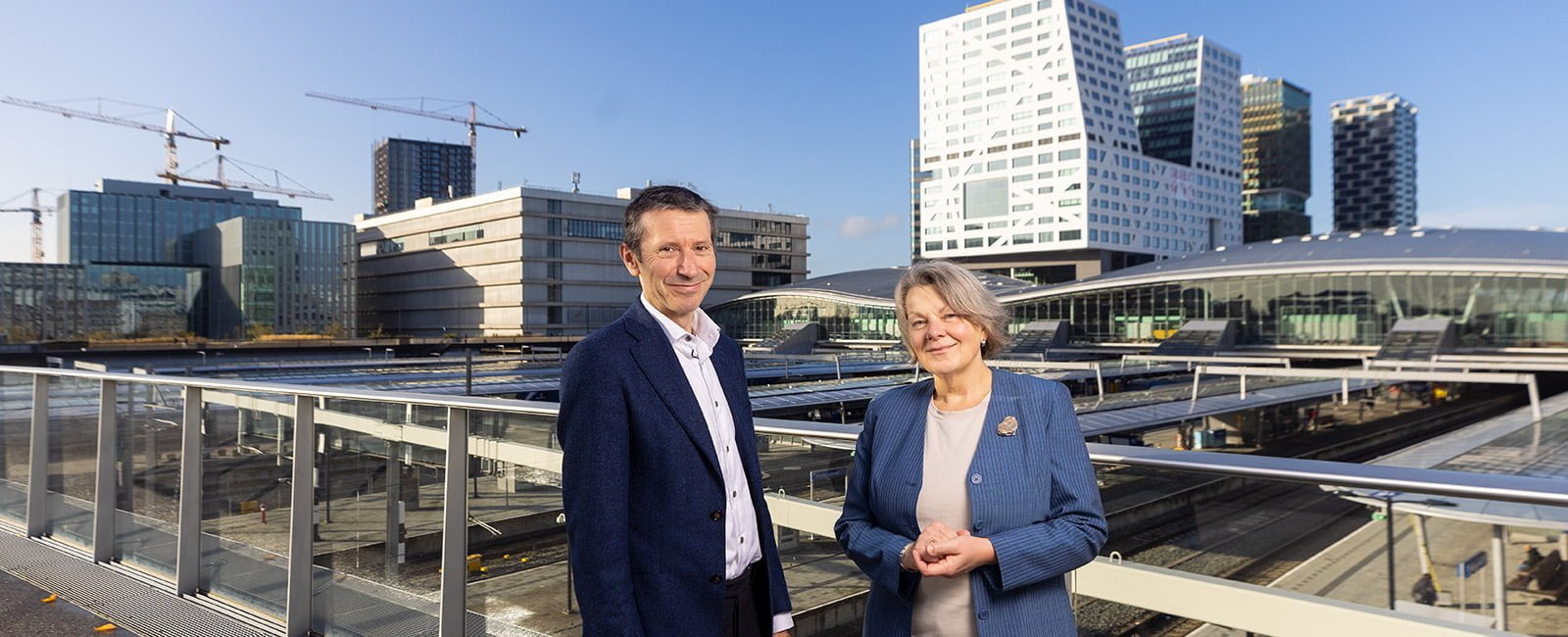 Jeroen en Carla staan bij Utrecht CS met uitzicht op stadskantoor