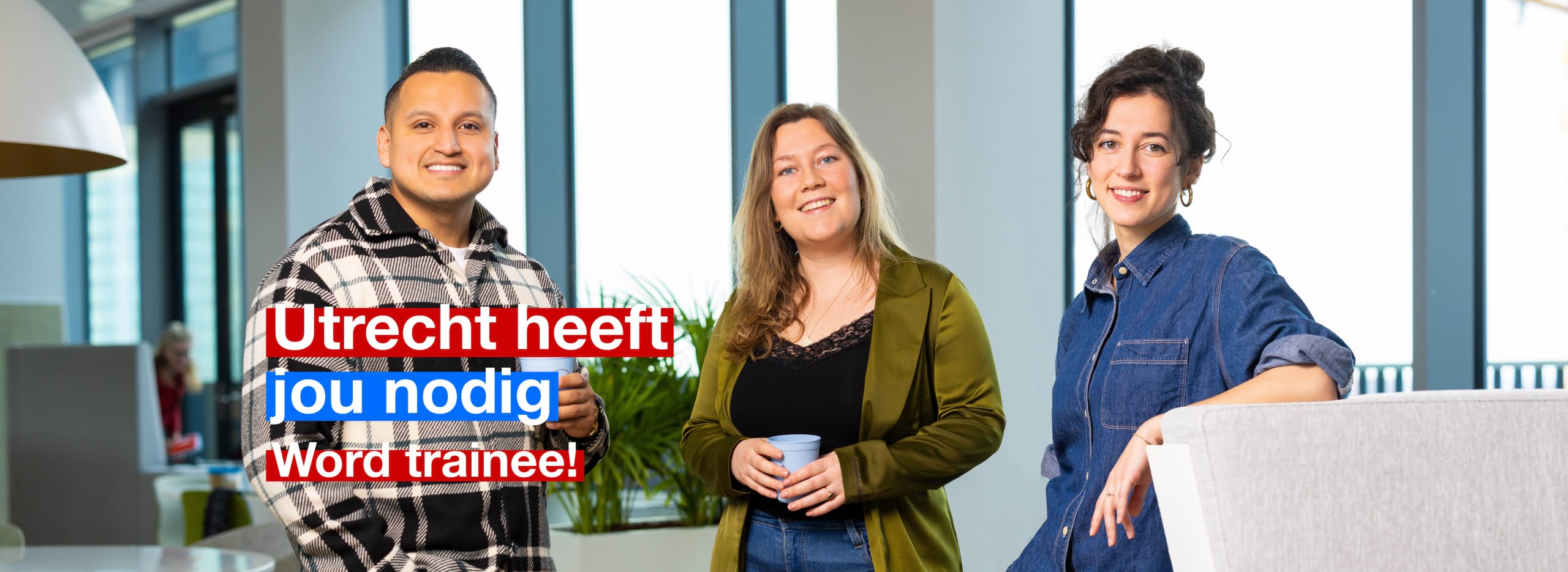 Drie trainees staan in het stadskantoor. Op de afbeelding staat de tekst 'Utrecht heeft jou nodig, word trainee'