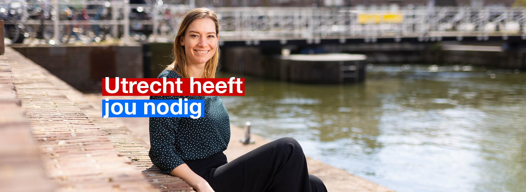 Vrouw zit langs de kade. In beeld staat de tekst Utrecht heeft jou nodig.