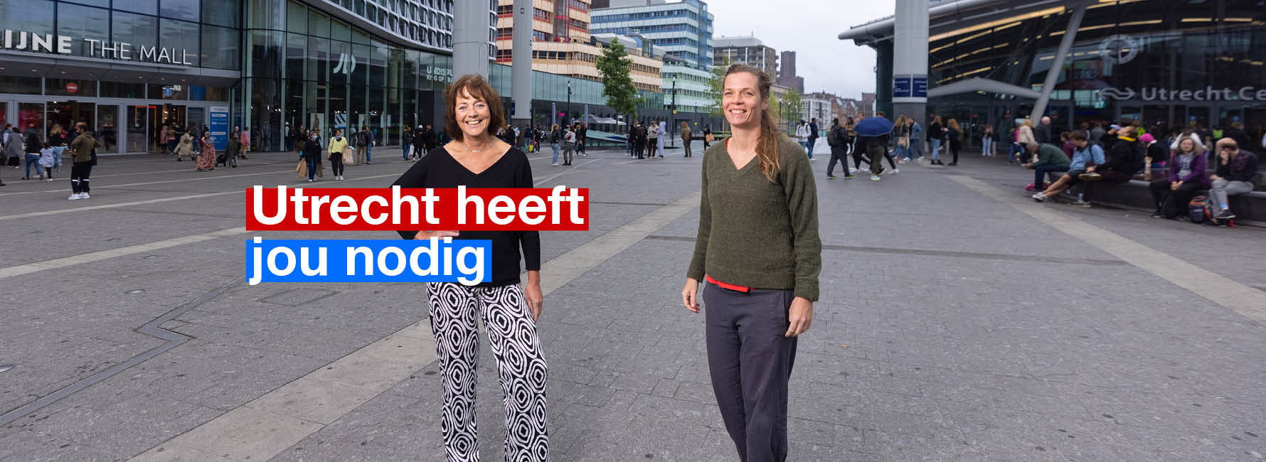 Twee vrouwen op het stationsplein. In beeld staat de tekst Utrecht heeft jou nodig.