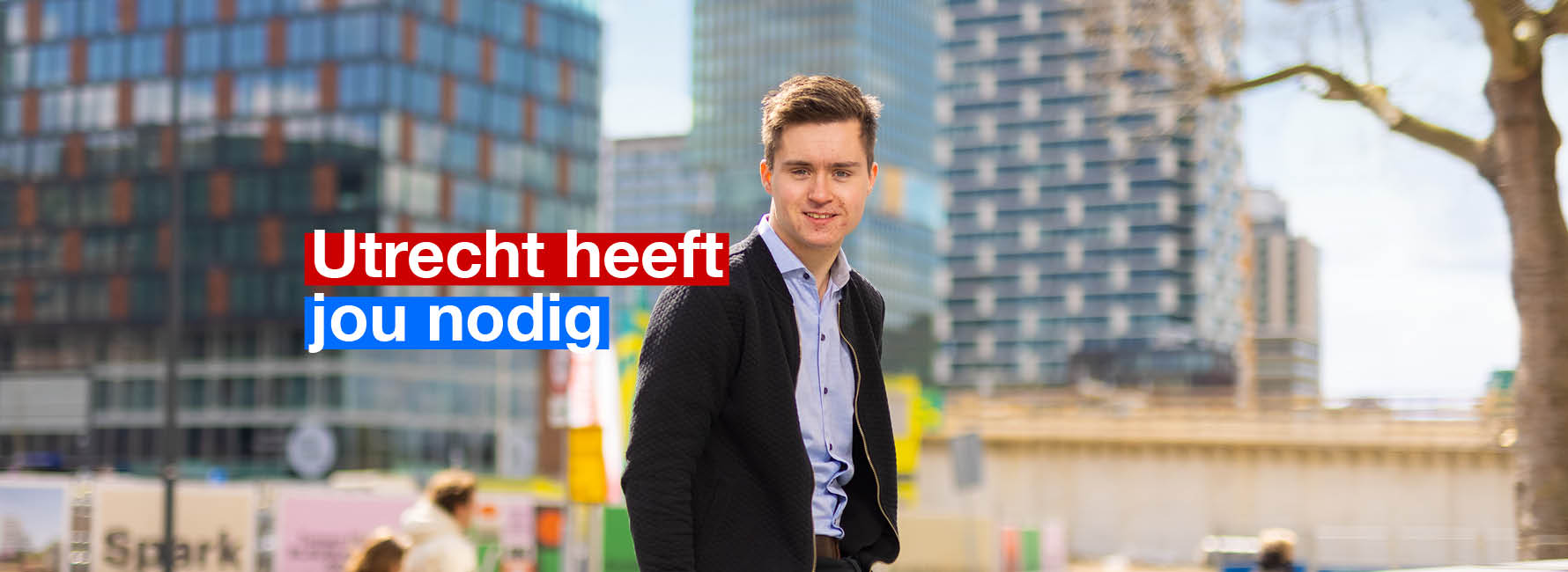 Iemand staat buiten voor een aantal gebouwen. In beeld staat de tekst Utrecht heeft jou nodig.
