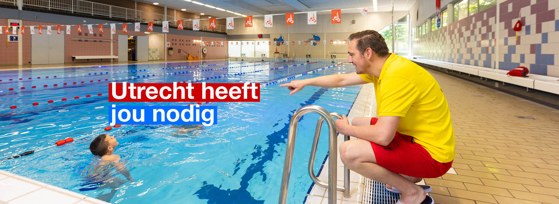 Een zwembadinstructeur hurkt bij het zwembad en geeft instructies. In beeld staat de tekst Utrecht heeft jou nodig.