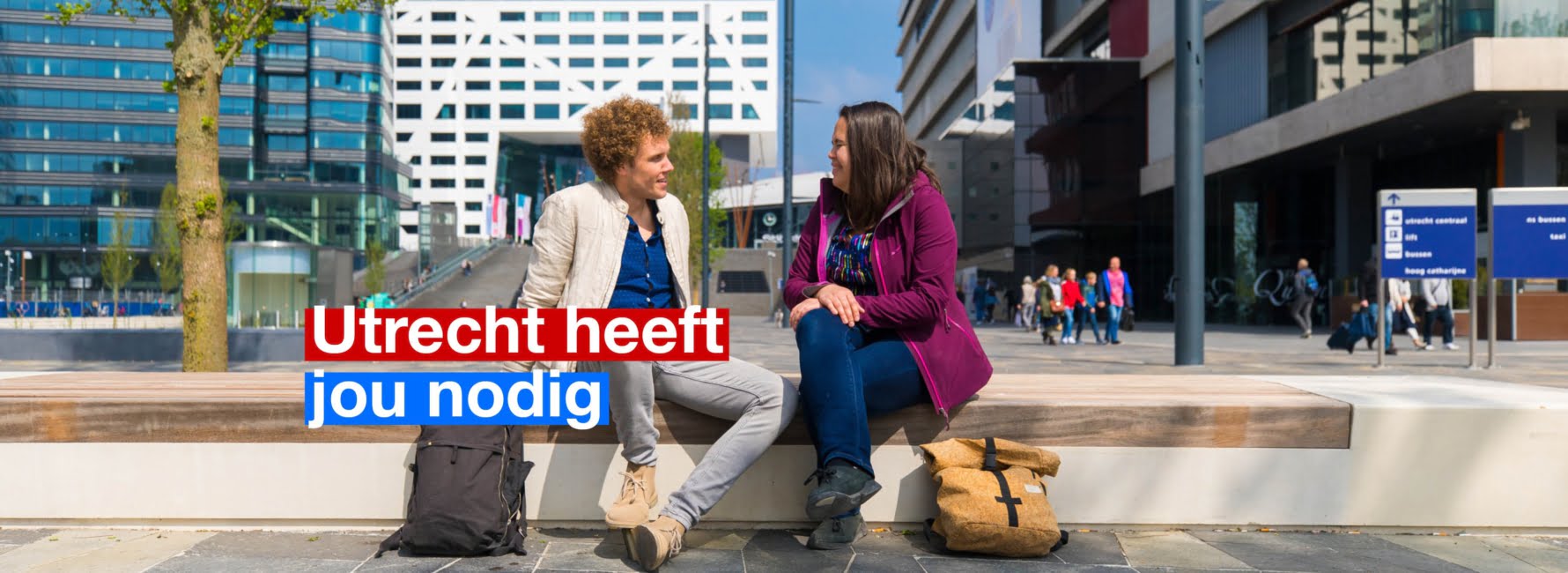 Twee mensen zitten op het jaarbeursplein. In beeld staat de tekst Utrecht heeft jou nodig.