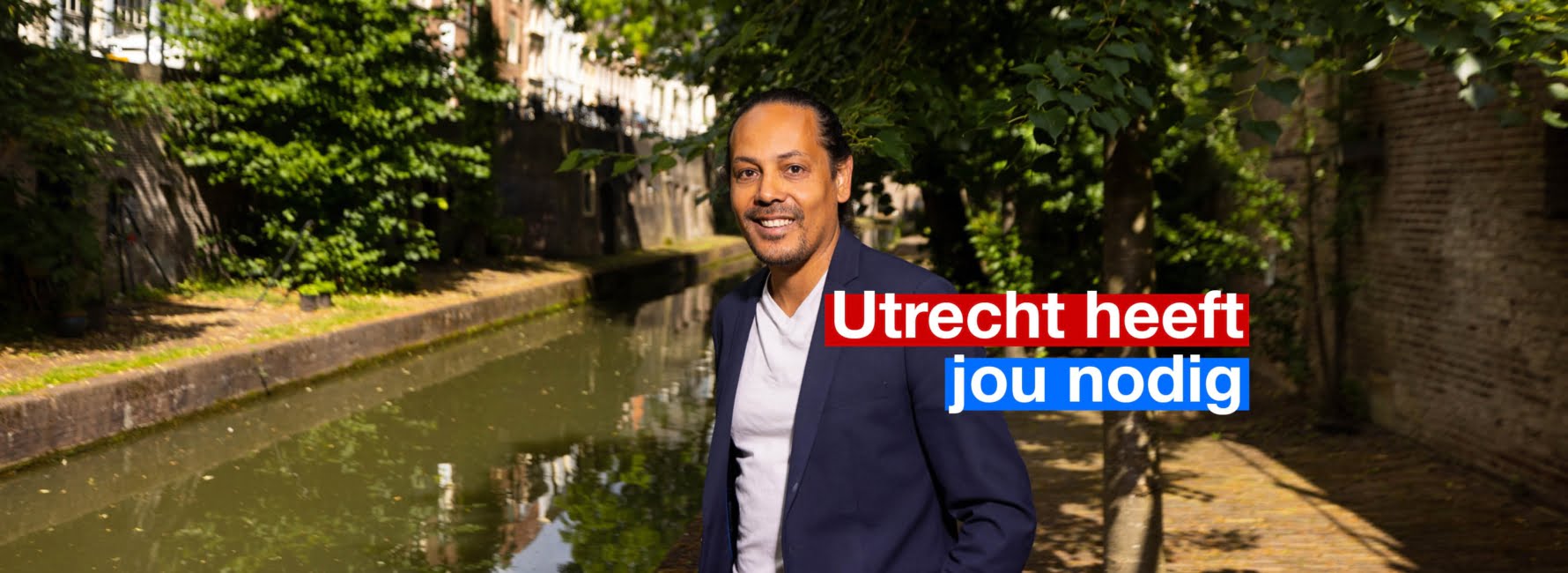 Iemand staat langs de oude gracht. In beeld staat de tekst Utrecht heeft jou nodig.
