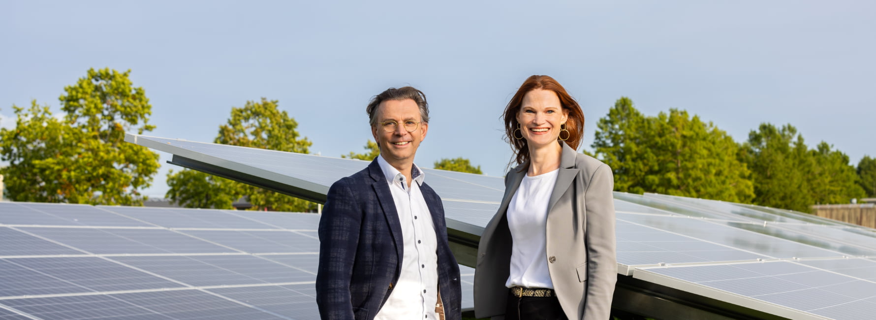 Twee medewerkers staan naast zonnepanelen.