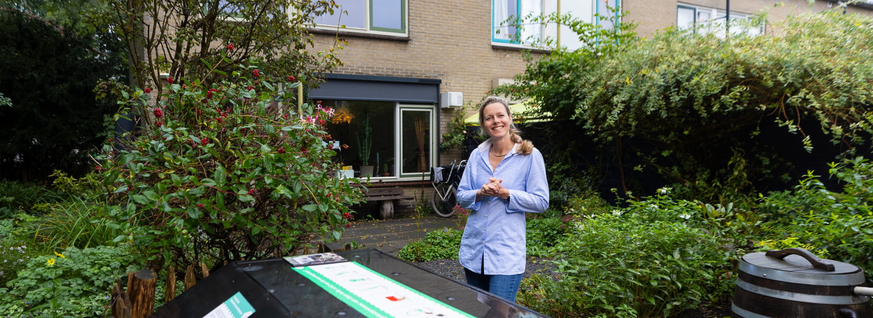 Een medewerker staat in de tuin van het Jouwhuisslimmer huis.