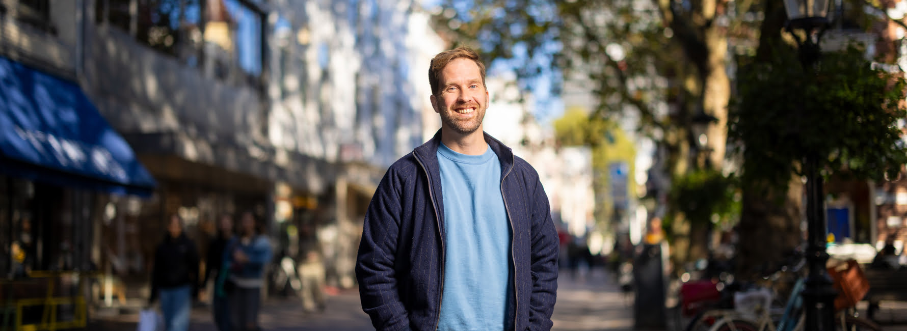 Een medewerker op een straat in Utrecht. Op de achtergrond is een stukje van de domtoren te zien.