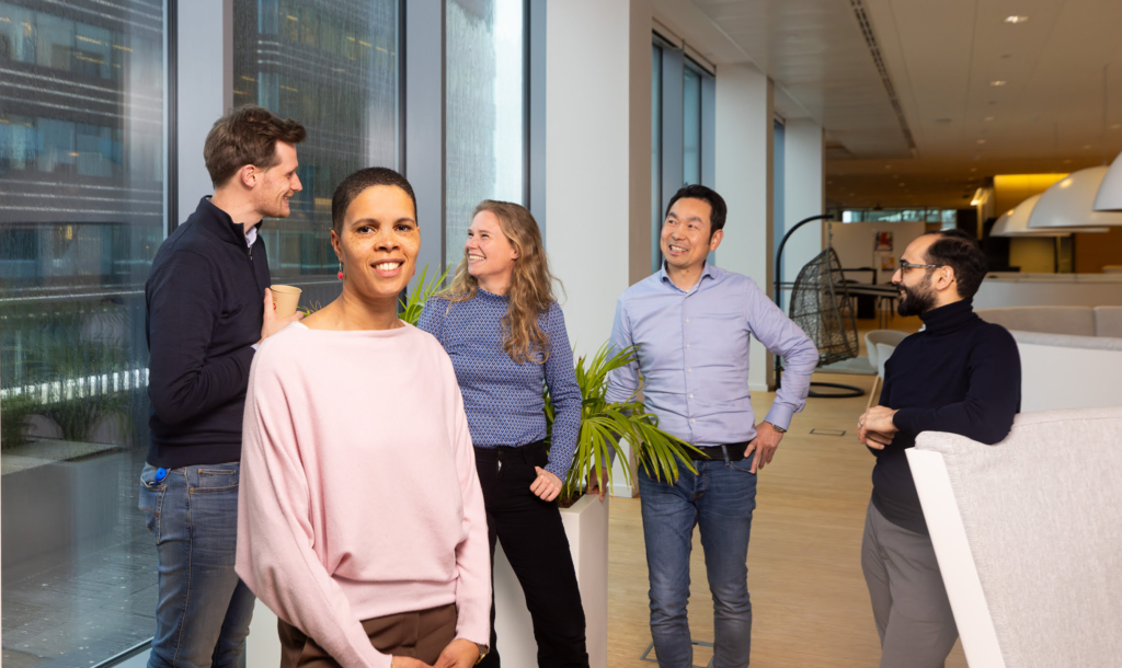 1 vrouw staat in beeld met achter haar 4 medewerkers, 2 mannen en een vrouw