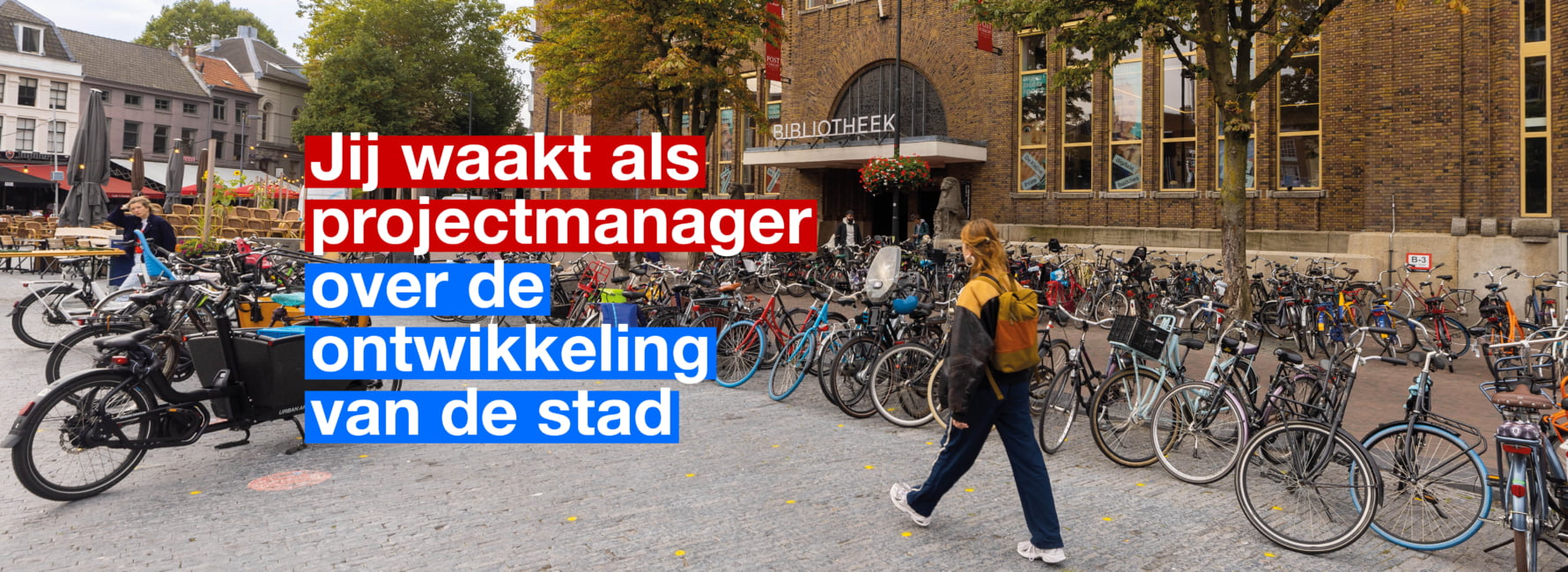 Persoon loopt voor de grote bibliotheek op het Neude omringt door fietsen