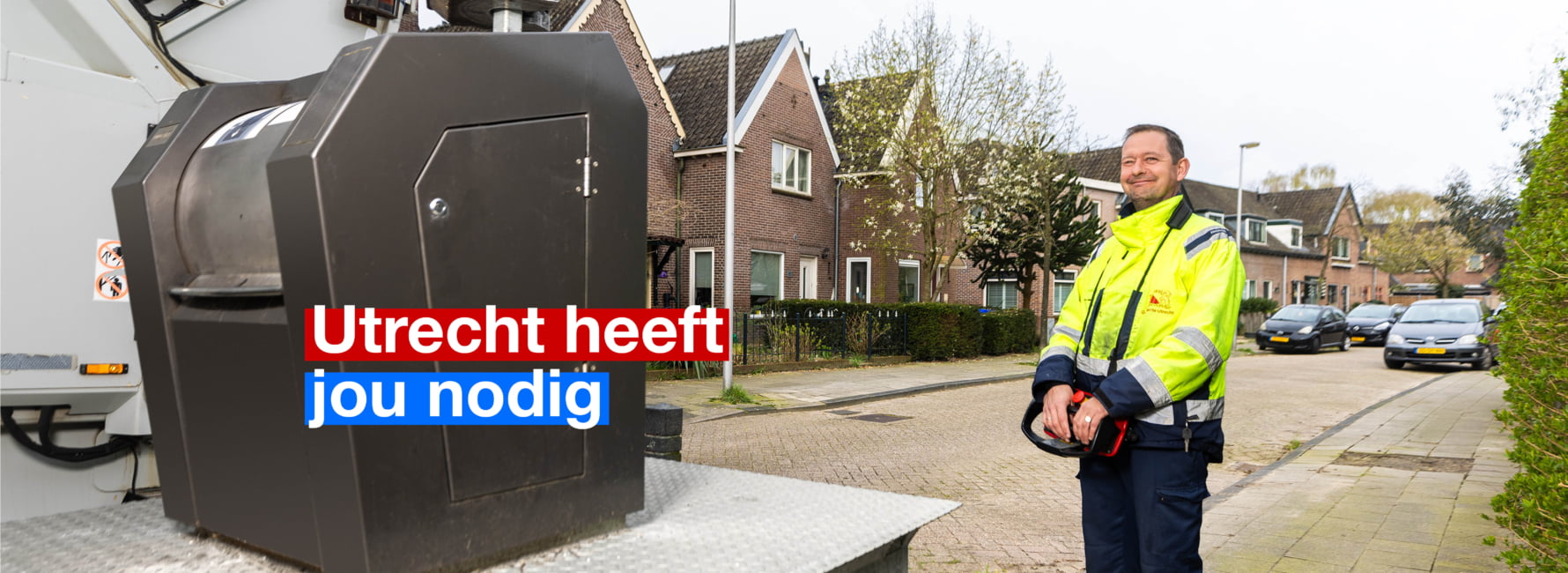 Een vrolijke medewerker van de afvalvoorziening die een ondergrondse container leeghaalt met de besturing van zijn vuilniswagen.