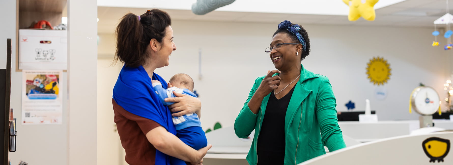 Een jeugdverpleegkundige vrouw die in gesprek is met een moeder en pasgeboren baby