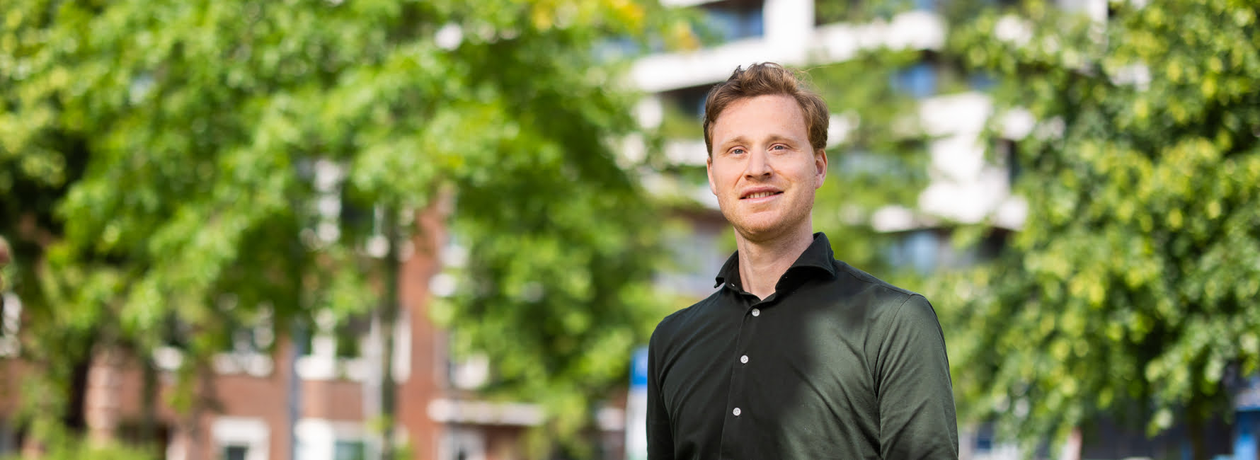 Een jurist staat tussen het groen en de bomen voor appartementencomplex Wonderwoods