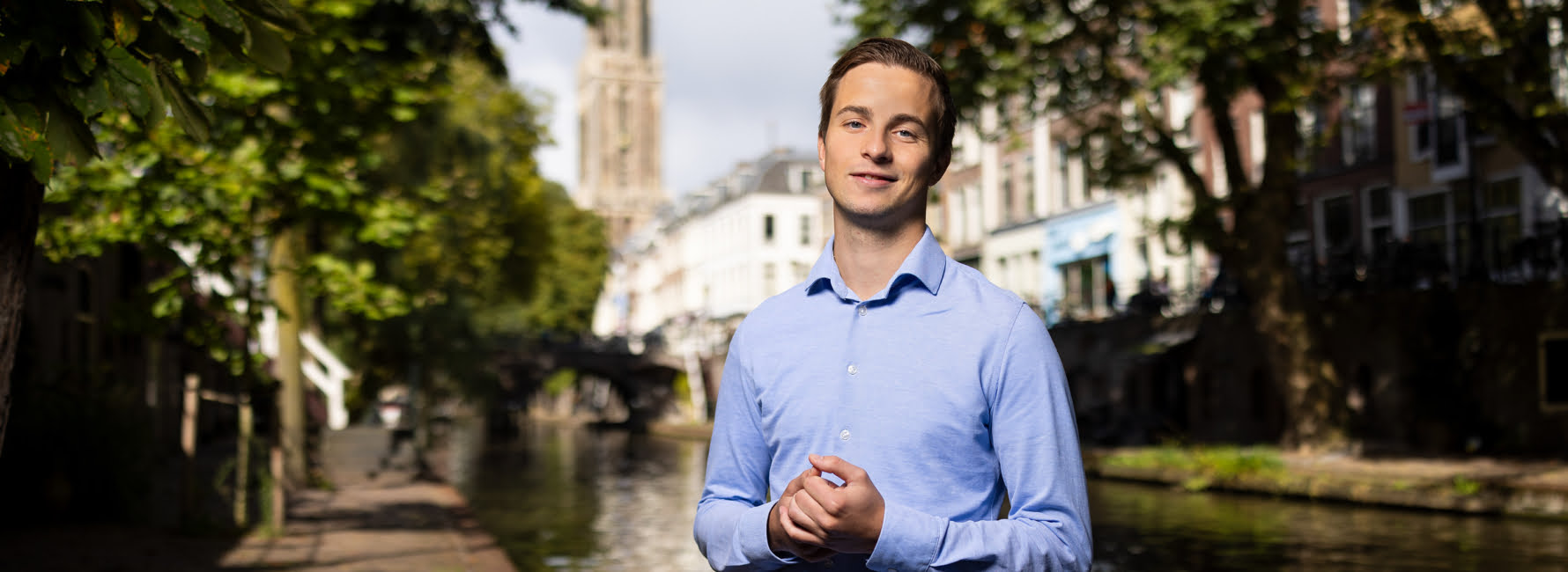 Tim staat aan de gracht van Utrecht voor de domtoren