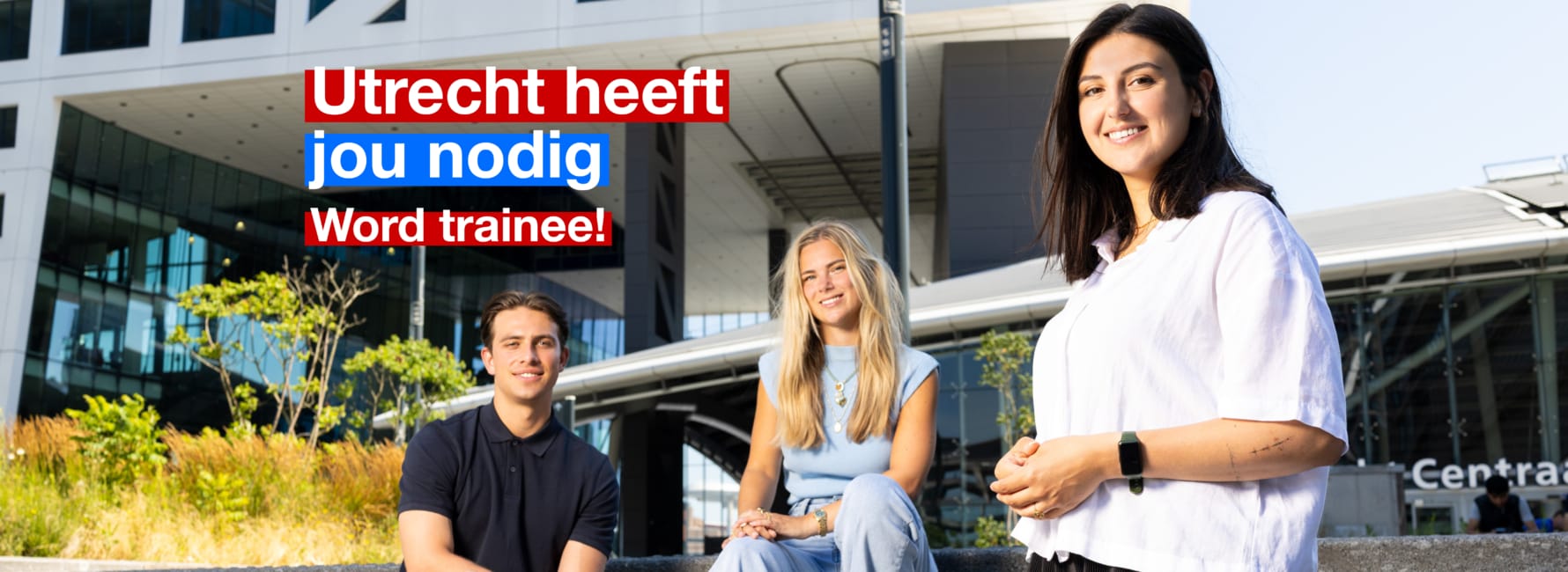 Drie medewerkers staan samen voor het stadskantoor Utrecht, met de tekst 'Word Trainee'