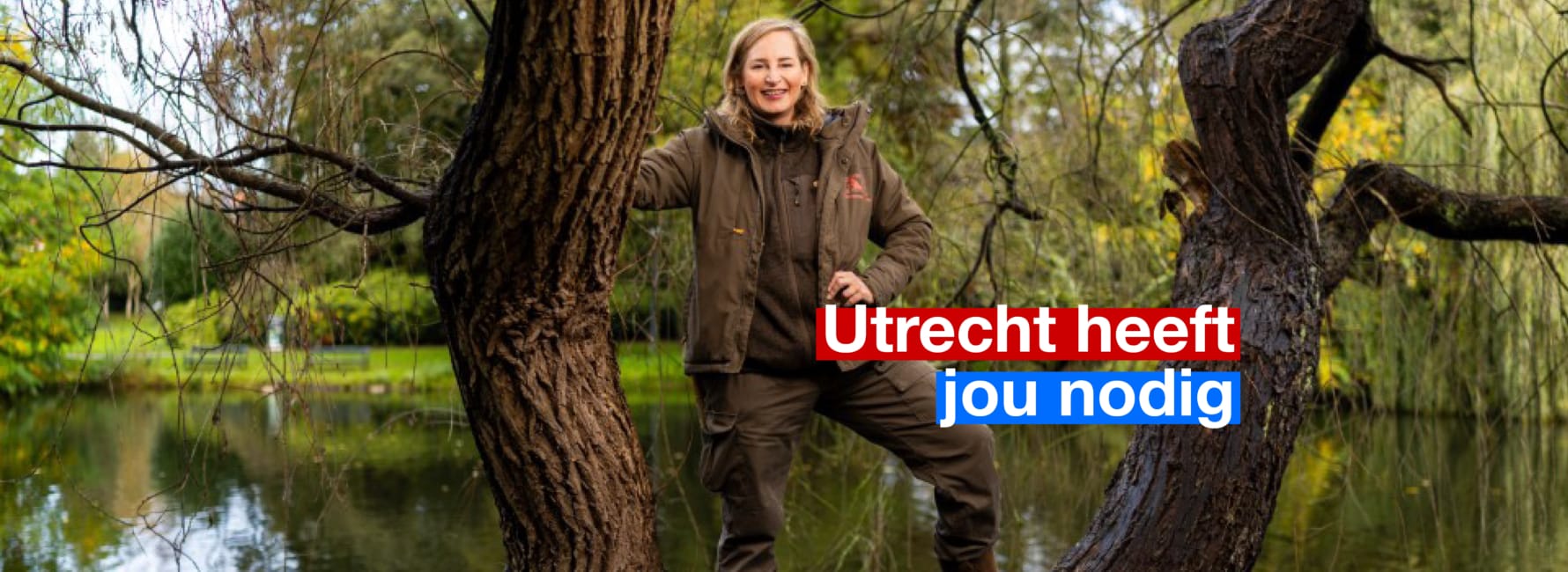 Een boomadviseur staat op een grote boom met een glimlach